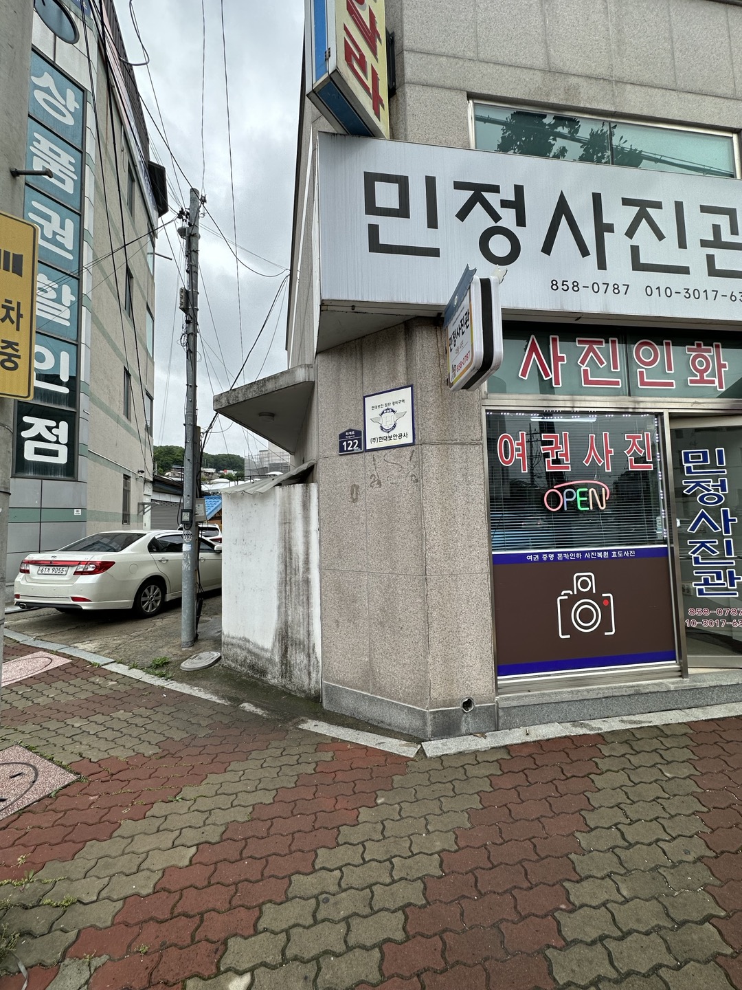  01 / 写真館の隣の路地へ  大通りで写真館の看板を見つけたら、隣の路地へ。写真の大通り側の車の位置ではなく、路地内の指定スペースにお停めください。 